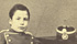 Ritratto a figura intera di Priamo Gallisay adolescente, in divisa,  seduto,  in un interno di studio fotografico. Stampa fotografica all’albumina di A. Andreotti e C., Firenze, 2° metà '800